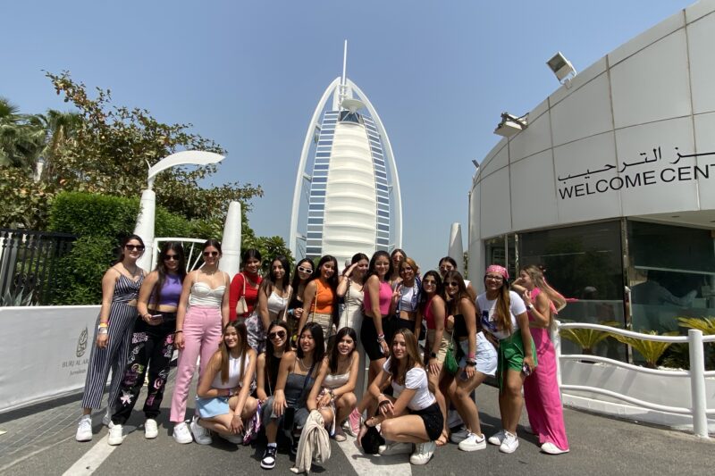 Grupo de quinceañeras frente al hotel Burj Al Arab en Dubái durante un tour internacional.