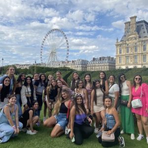 Grupo de quinceañeras en los Jardines de las Tullerías en París con la rueda panorámica al fondo.
