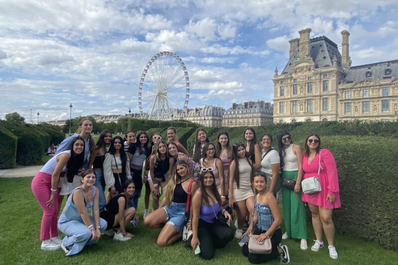Grupo de quinceañeras en los Jardines de las Tullerías en París con la rueda panorámica al fondo.
